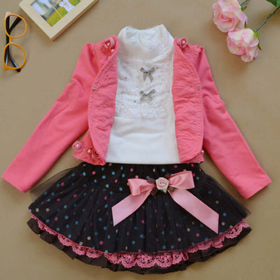 0-9Y Ruffle Tracksuit -Children's outfit with pink jacket, white top, and black polka dot skirt on a beige surface.