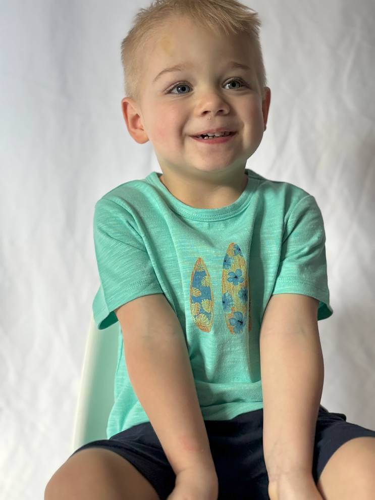 aqua-surfboard-printed-tee-Child wearing a green t-shirt with a graphic design on a white background