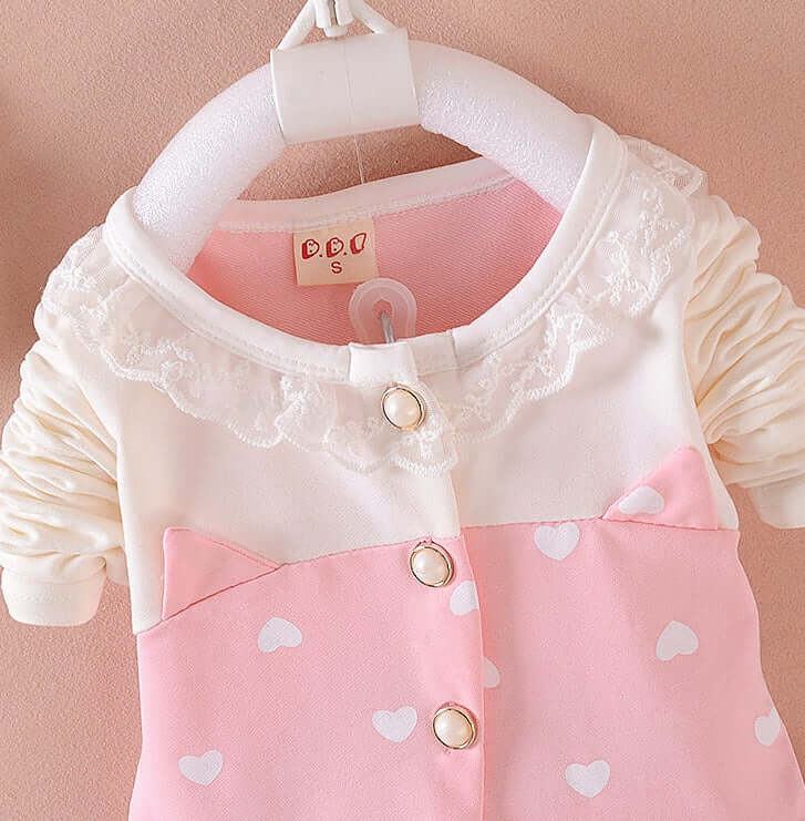 BibiCola Baby Girls - Pink and white children's outfit with lace details on a pink background