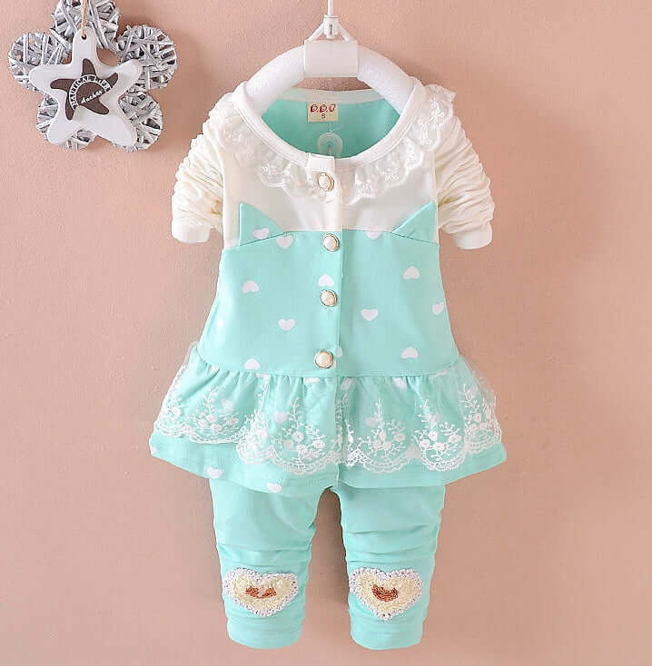 BibiCola Baby Girls - Children's outfit with a white lace top and light blue dress with heart patterns on a beige background.