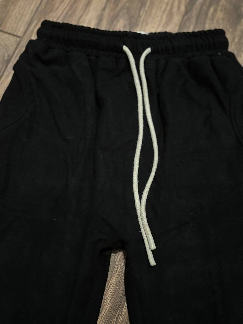 Black pants with a white drawstring on a wooden floor