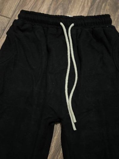 Black pants with a white drawstring on a wooden floor