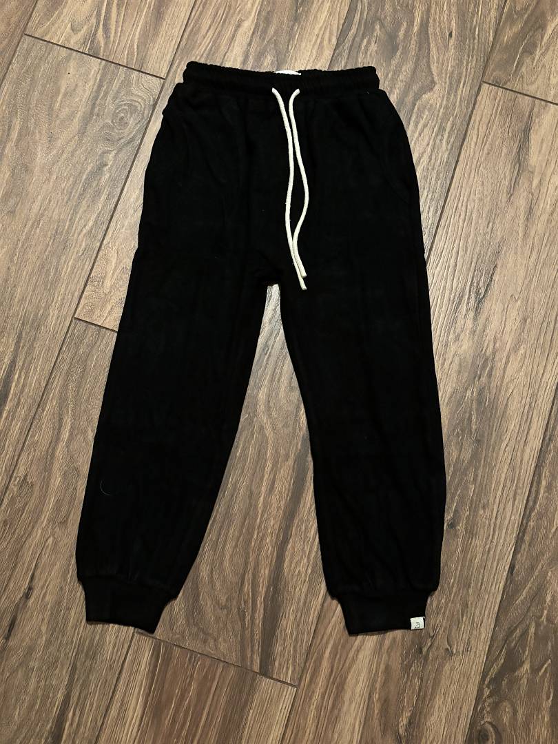 Black sweatpants with a white drawstring on a wooden floor