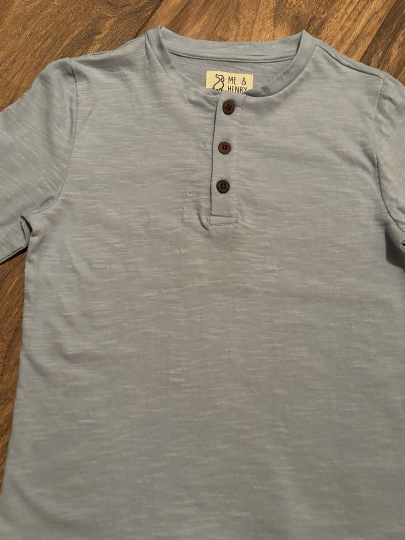 Gray henley shirt with brown buttons on a wooden surface