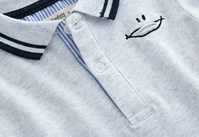 Childrens Polo Shirt -Close-up of a baby outfit with embroidered face design on a white background