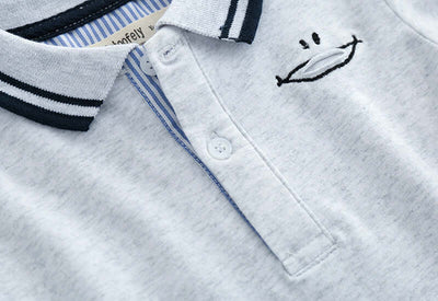 Childrens Polo Shirt -Close-up of a baby outfit with embroidered face design on a white background