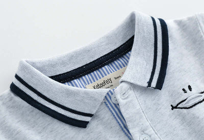 Childrens Polo Shirt -Close-up of a children's polo shirt with striped collar and embroidered design on a light background