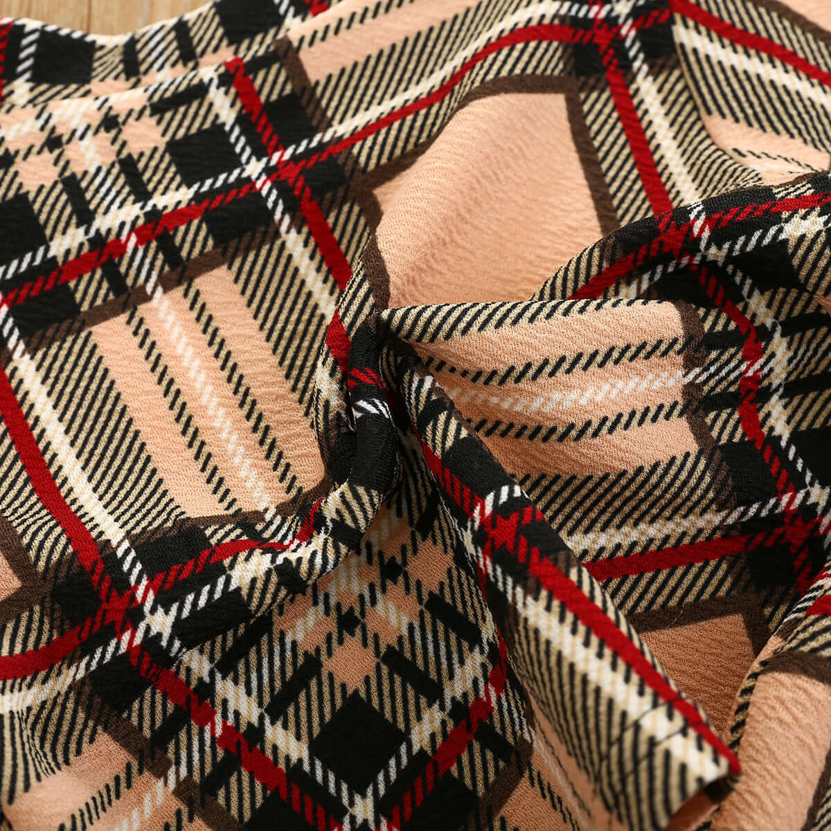 Girls Fashion Plaid-Close-up of plaid fabric with black, red, and beige colors.
