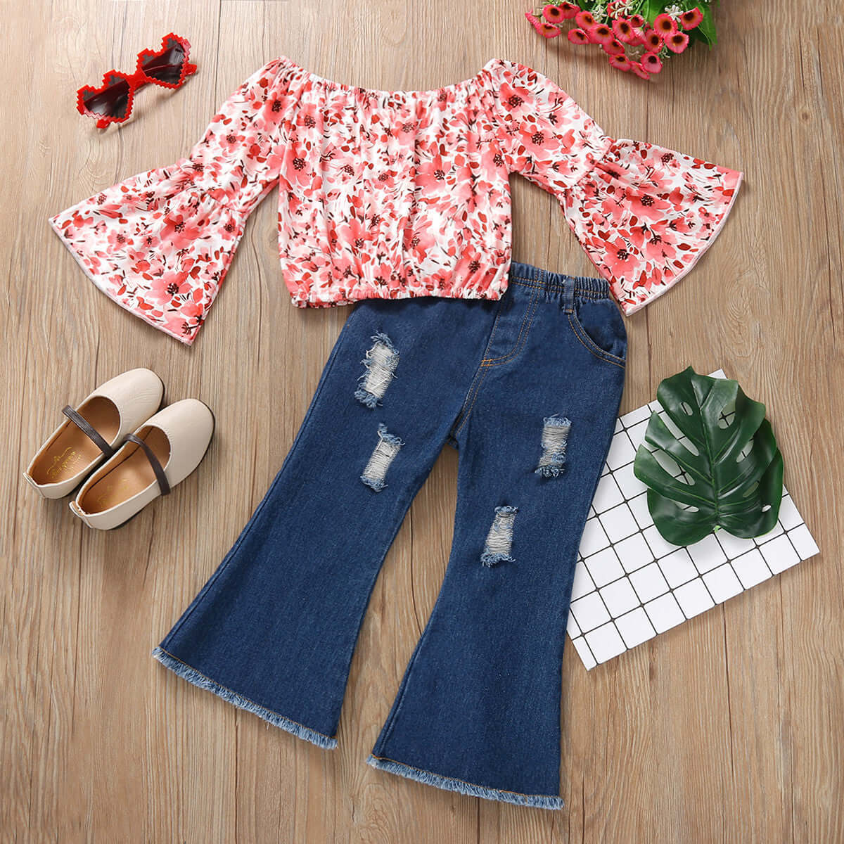 Girls Flared Sleeve Top Denim Trousers-Floral blouse with bell sleeves and distressed jeans on a wooden surface.