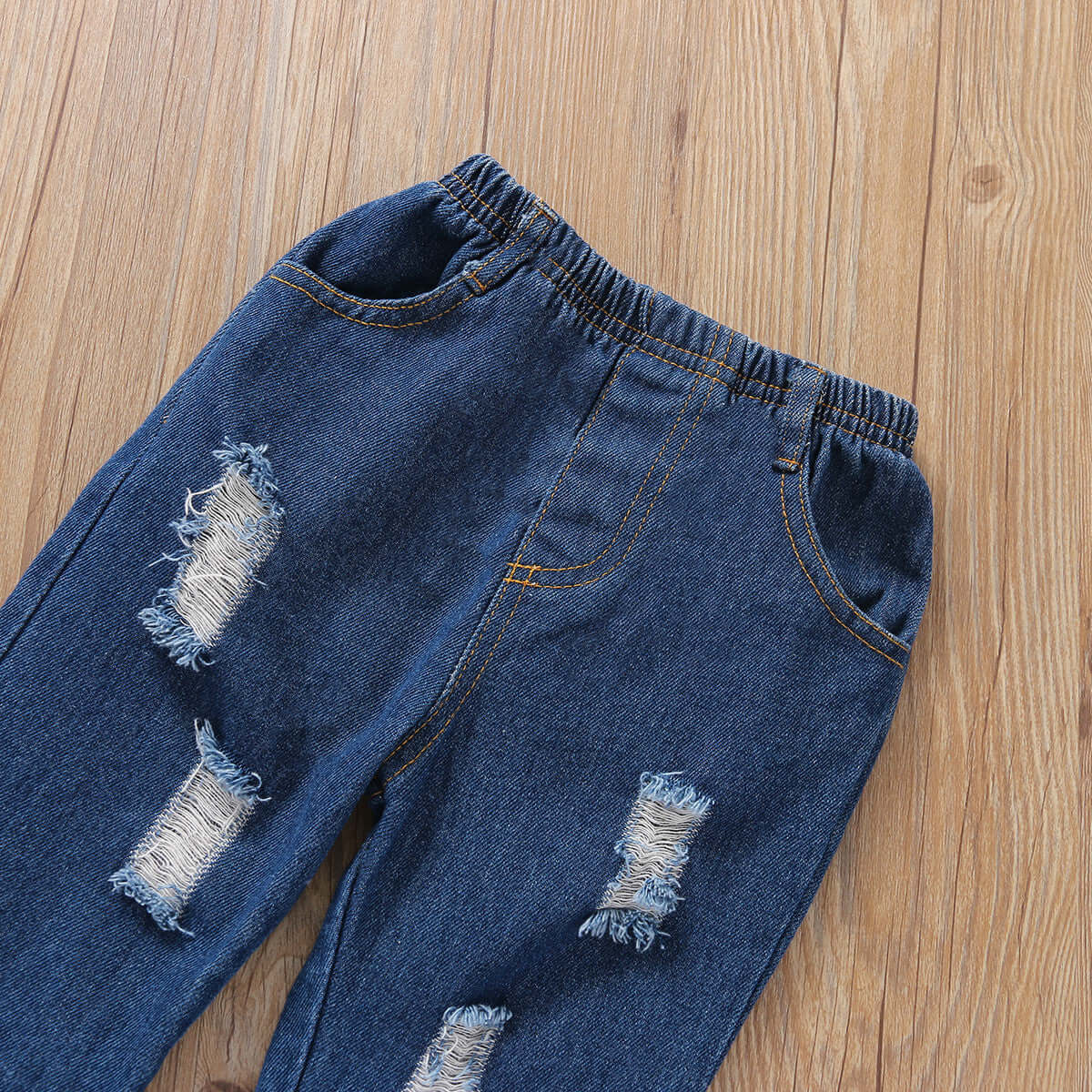 Girls Flared Sleeve Top Denim Trousers-Distressed blue jeans on a wooden surface