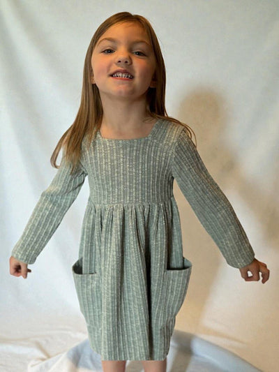 Young girl wearing a green checkered dress against a plain background