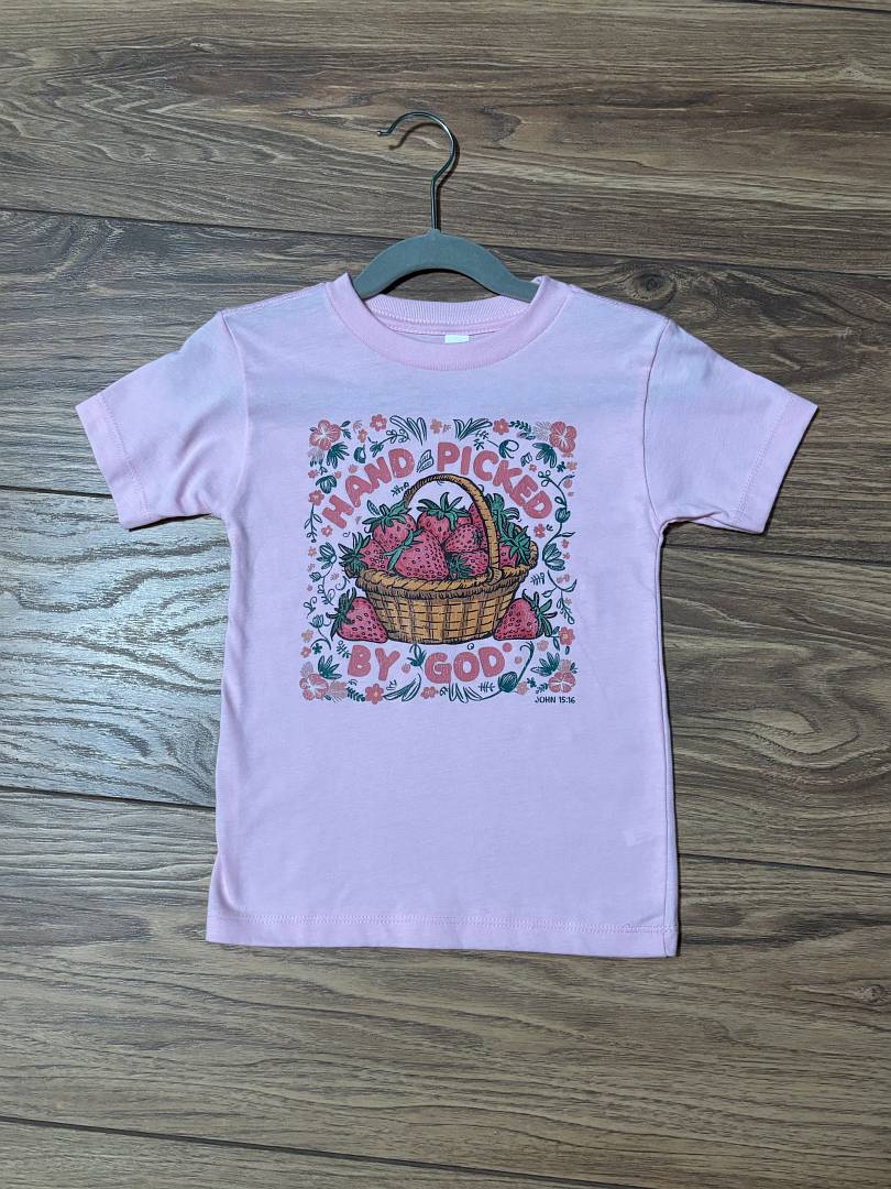 Pink t-shirt with graphic design on a wooden surface
