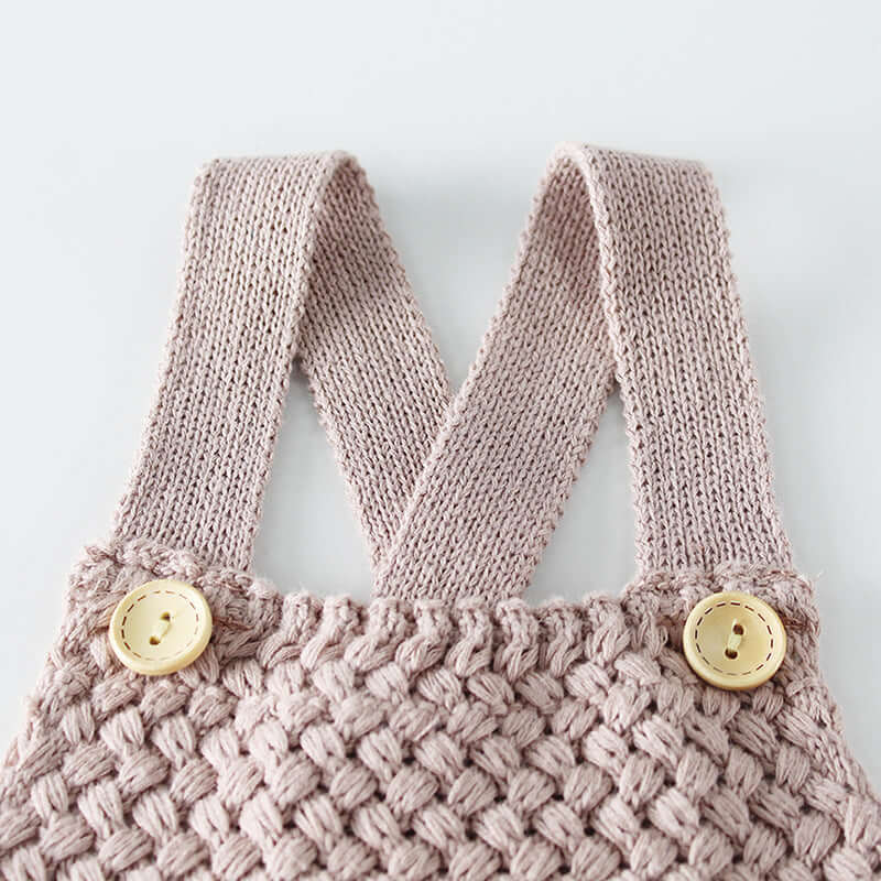 Knitted woolen bodysuit-Knitted pink baby romper with button details on a light gray background