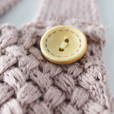 Knitted woolen bodysuit-Close-up of a yellow button on a knitted fabric background