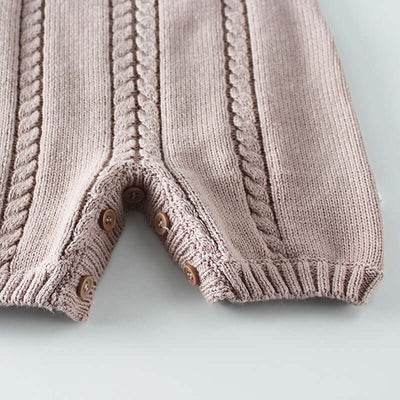 Knitted woolen bodysuit-Close-up of a pink knitted baby romper with button details on a light gray background