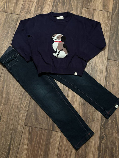 Navy sweatshirt with a dog graphic and dark jeans on a wooden floor.