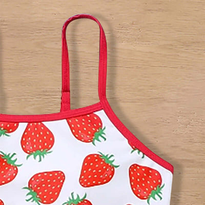 Childrens Swimsuit Three-piece-Strawberry-patterned top with red straps on a wooden surface