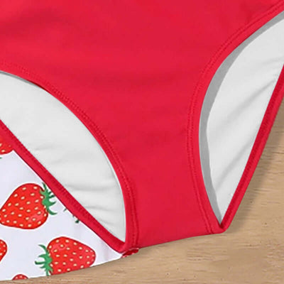 Childrens Swimsuit Three-piece-Red swimsuit with strawberry pattern on a wooden surface