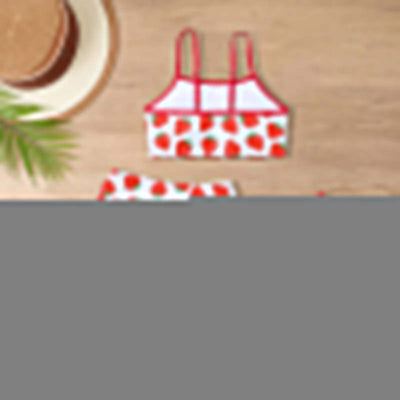 Childrens Swimsuit Three-piece-Strawberry-patterned two-piece swimsuit on a wooden surface with a hat and starfish.