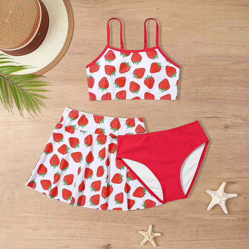Childrens Swimsuit Three-piece-Two-piece swimsuit with strawberry pattern on a wooden surface with a hat and starfish.
