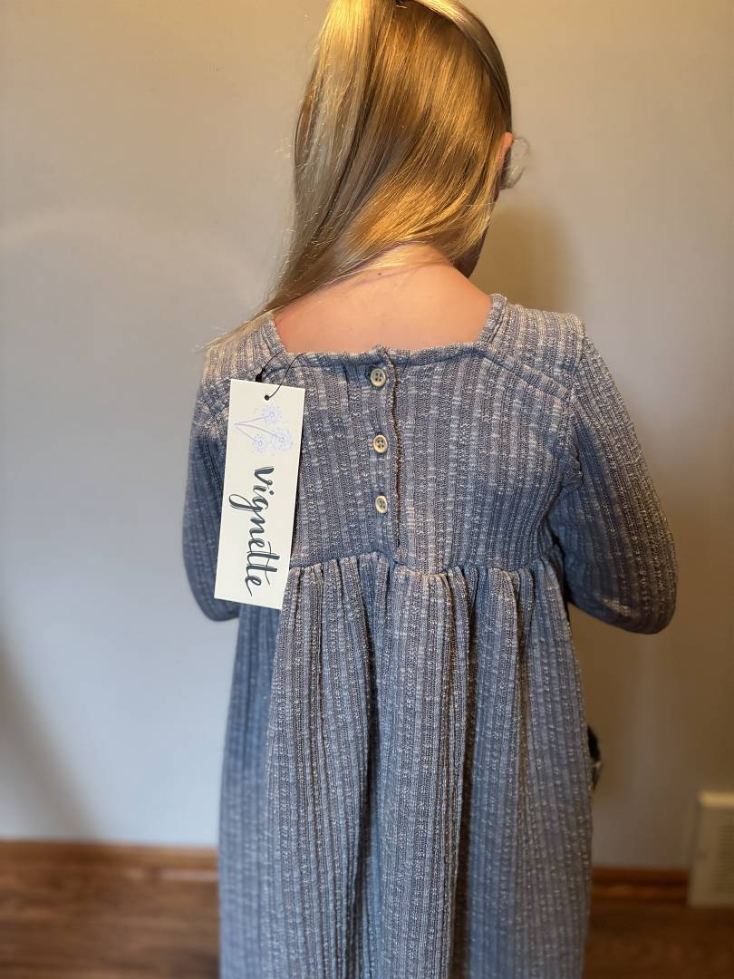 Person wearing a charcoal dress with a visible brand tag against a plain background