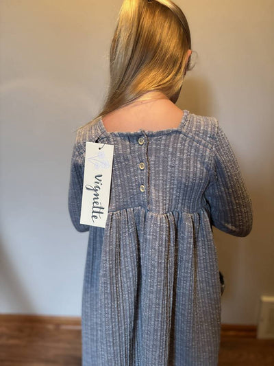 Person wearing a charcoal dress with a visible brand tag against a plain background