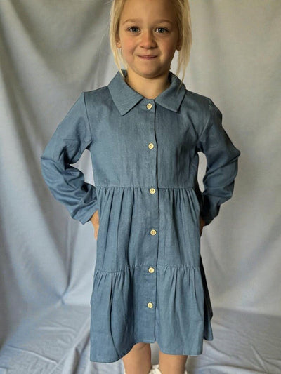 Young girl wearing a blue dress with a collar against a plain background