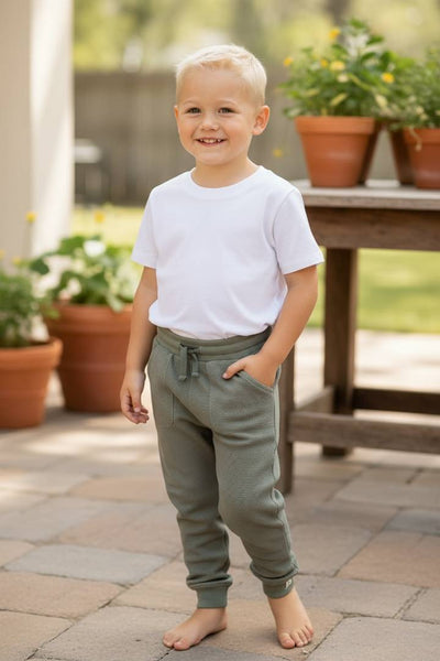 WES Waffle Jogger Pant-Young boy in a white shirt and green pants standing outdoors on a patio.